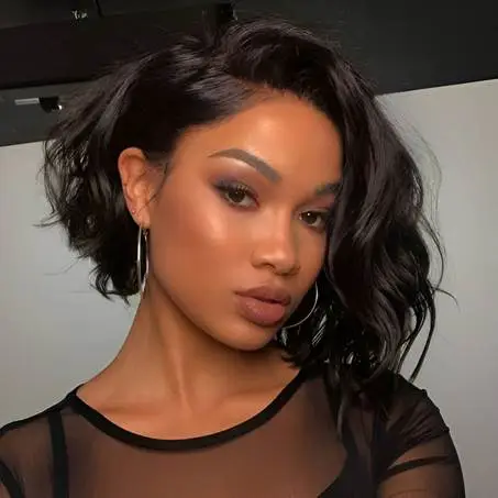 Young woman with wavy hair and hoop earrings in a sheer black top