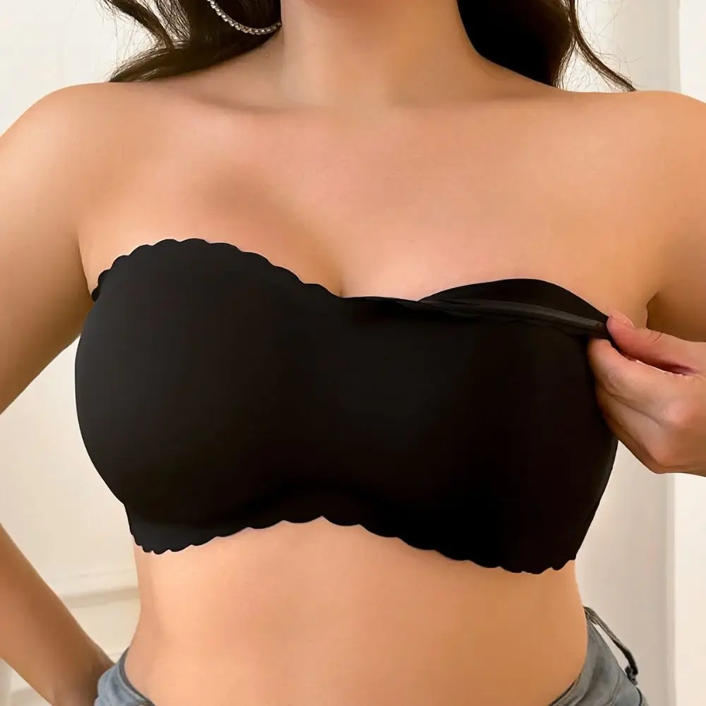 Person adjusting black strapless bra in indoor setting with light walls