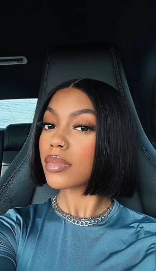Young woman with sleek bob hairstyle sitting in car, wearing a chain necklace