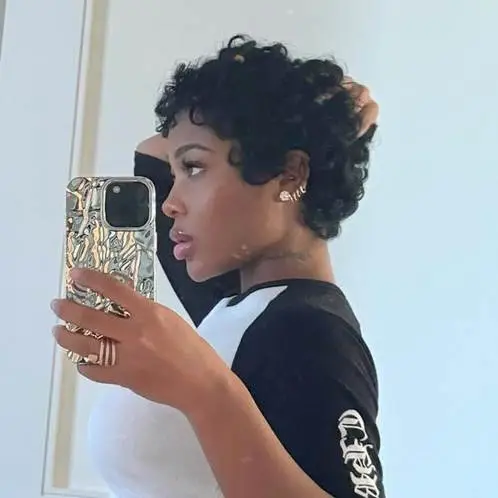 Short-haired woman in black and white shirt taking a mirror selfie indoors