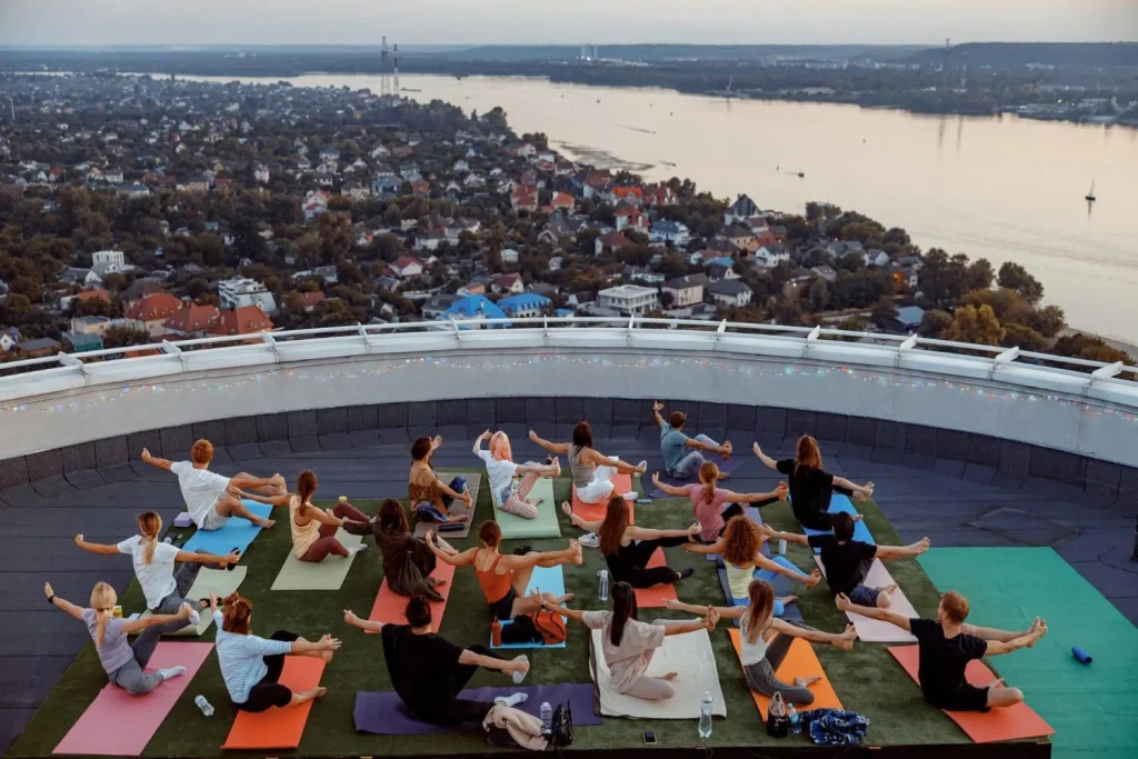Group practicing yoga on rooftop overlooking cityscape and river at sunset