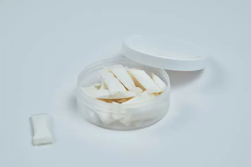 Small white pouches inside open circular container on plain light background