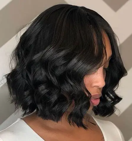 Black wavy bob hairstyle on person in white shirt against geometric patterned background