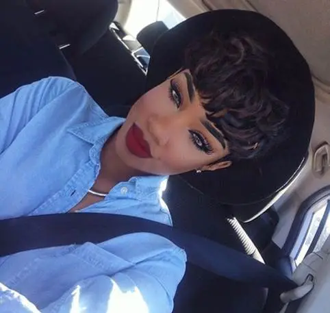 Woman wearing a blue denim shirt and black hat seated in a car with seatbelt on