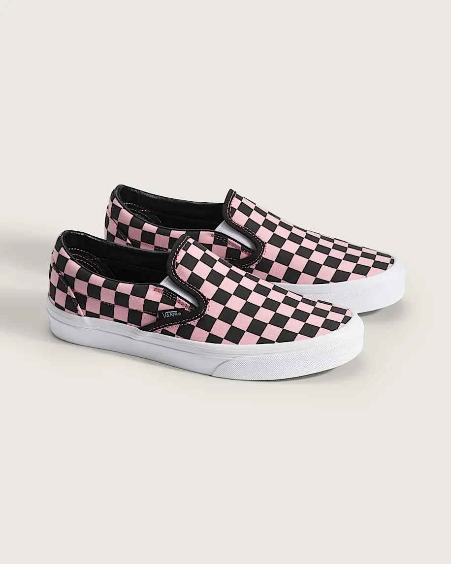 Pink and black checkered slip-on sneakers with white soles on a light background