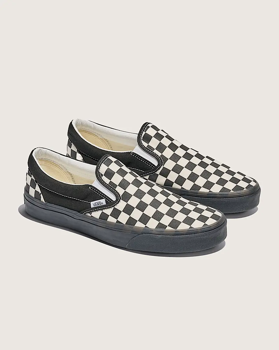 Checkerboard slip-on sneakers with black soles on light background