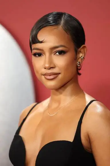Young woman with short hair and hoop earrings in elegant black dress against red background