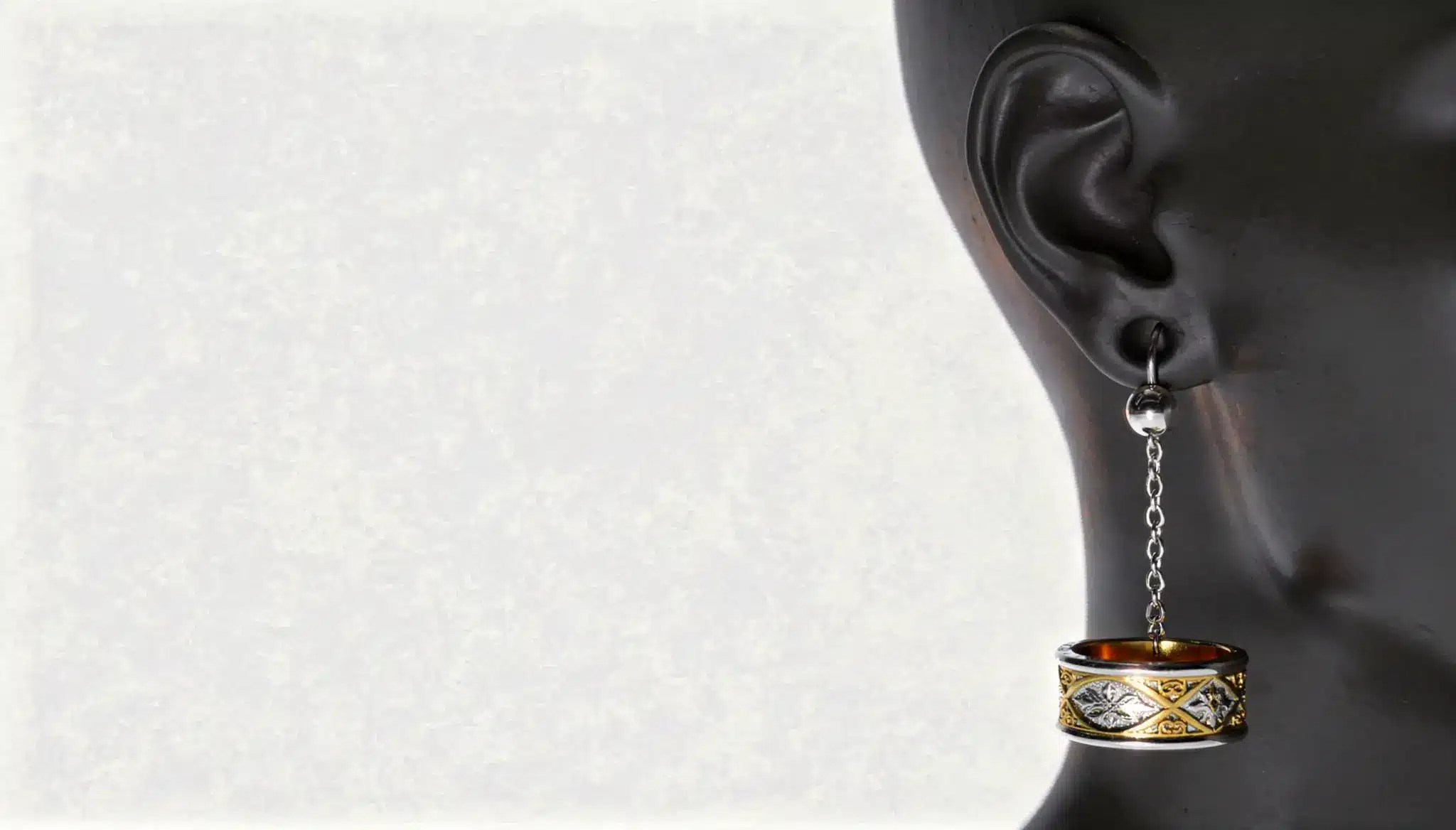 Black mannequin ear wearing a dangling ornate ring-style Bajoran earring.