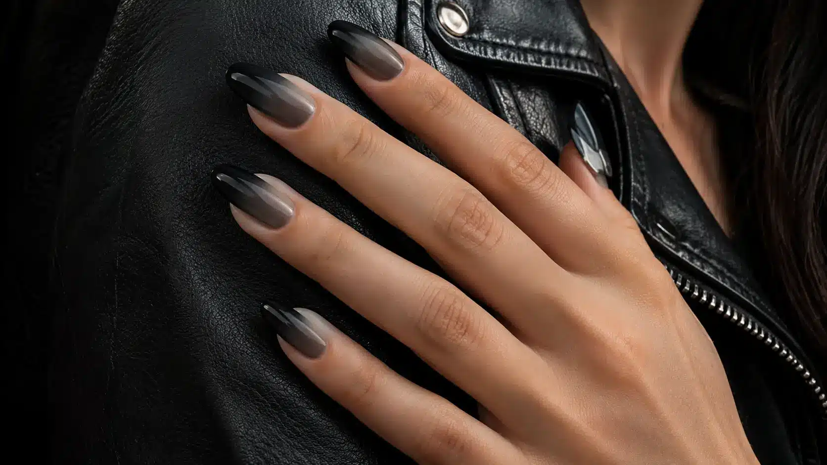 Black ombre nails resting on a black leather jacket