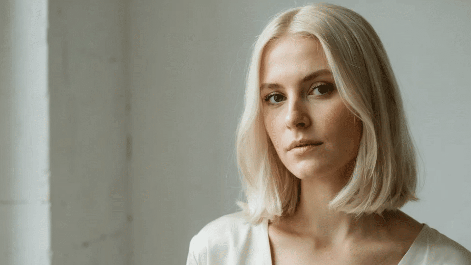 Woman with mid-length classic platinum blonde hair, smooth and polished for an evergreen look.