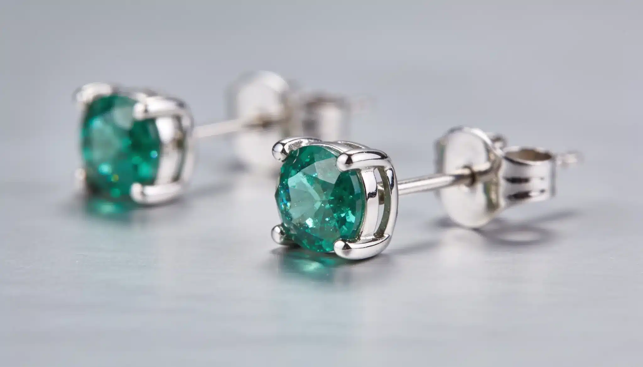 Clip-on earring with round green gemstone in a silver four-prong setting.
