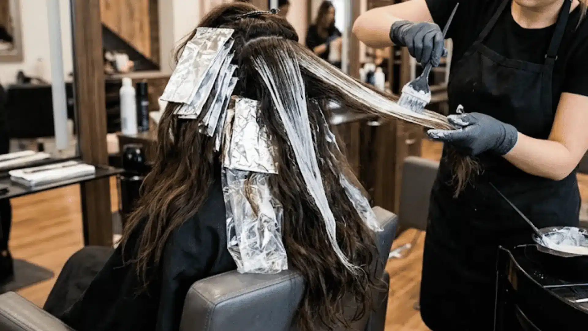 Foilyage technique showing balayage-style painted sections wrapped in foils for extra lift.