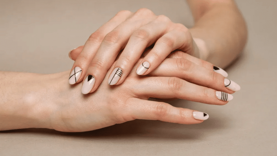 Hands featuring almond nails with geometric patterns in matte finish, structured modern manicure.