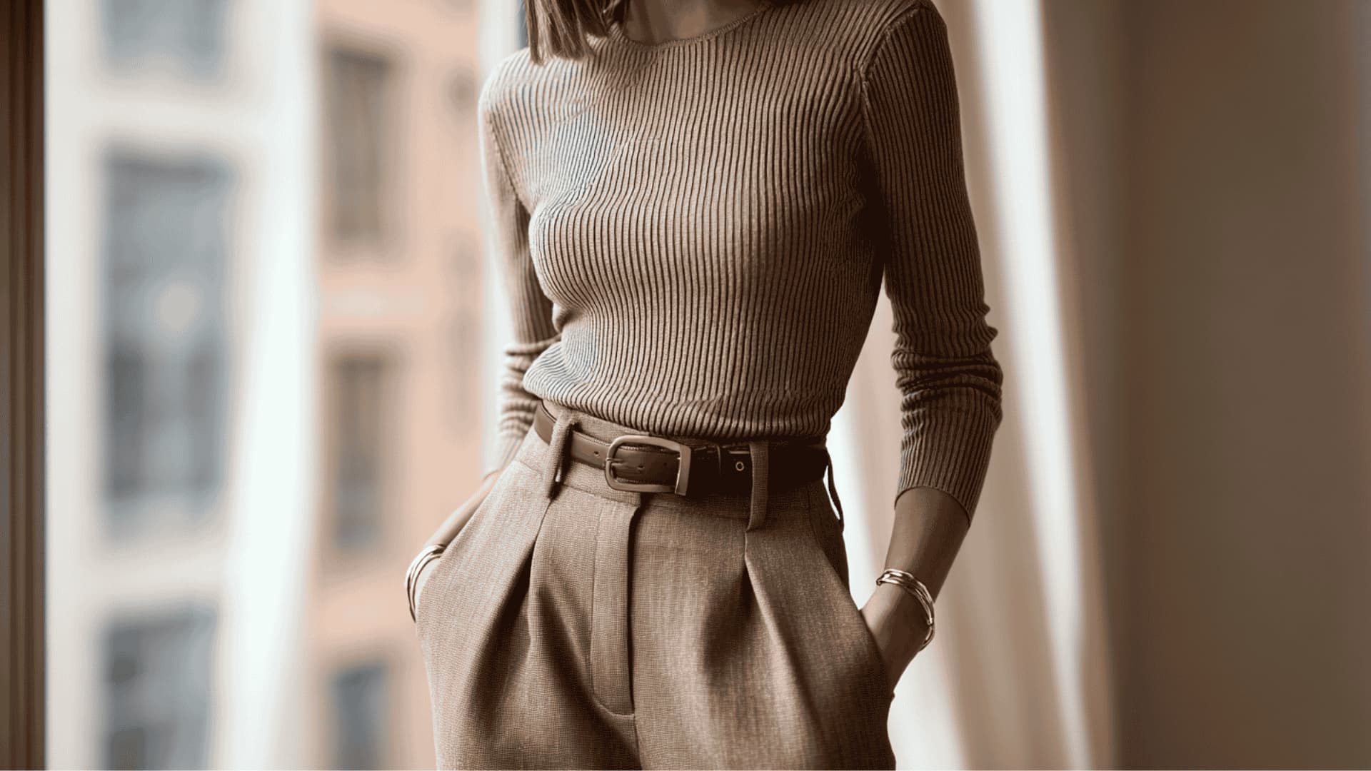 Woman in high-waisted trousers and a fitted knit top with hands in pockets