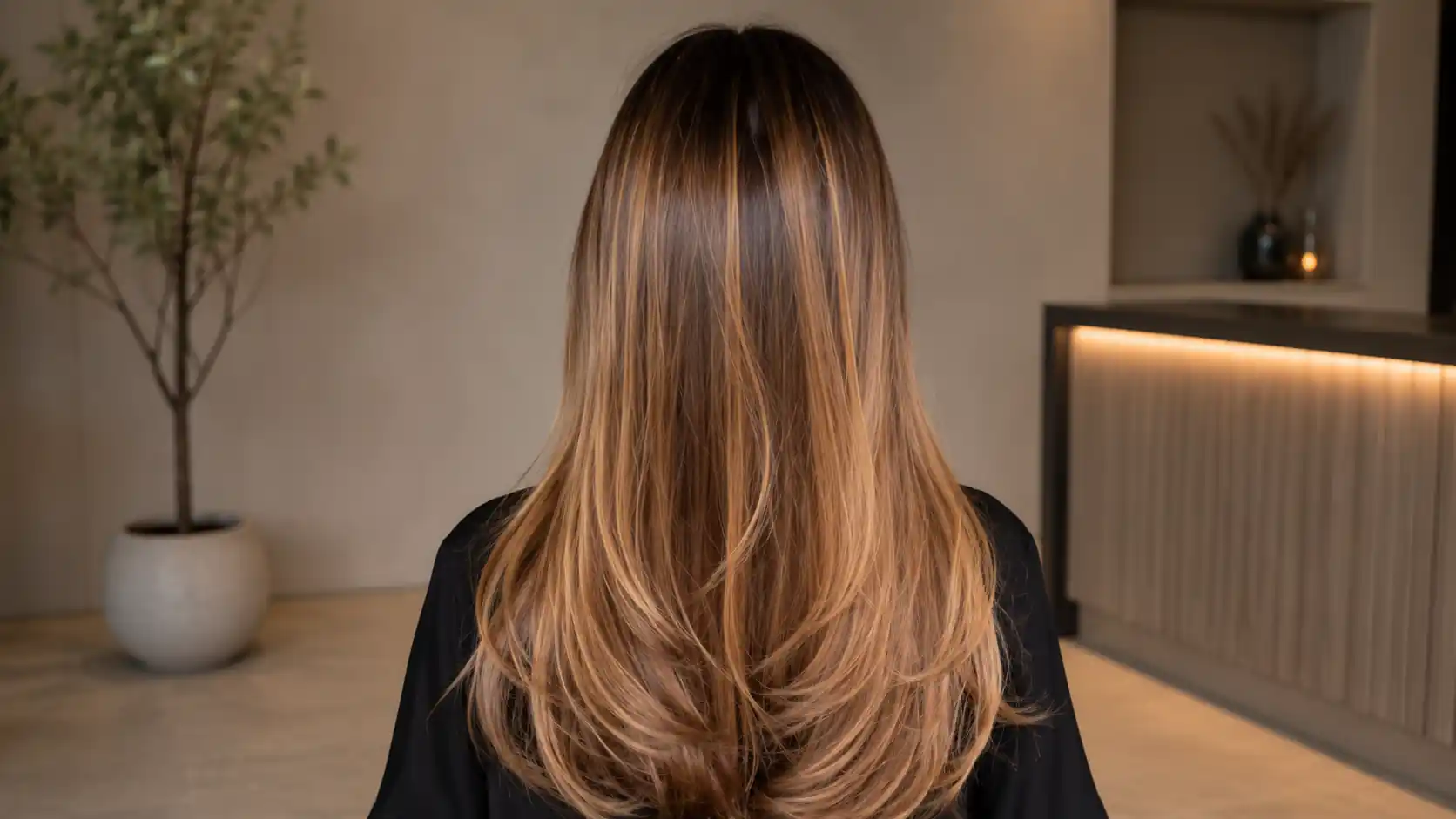 Black hair with fine honey brown babylights throughout, low-contrast warmth, subtle shimmer, medium hair length.
