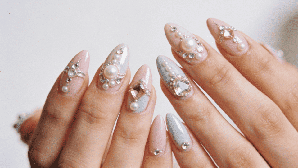 Hands featuring almond nails with jewel accents like rhinestones and pearls, polished luxurious look.