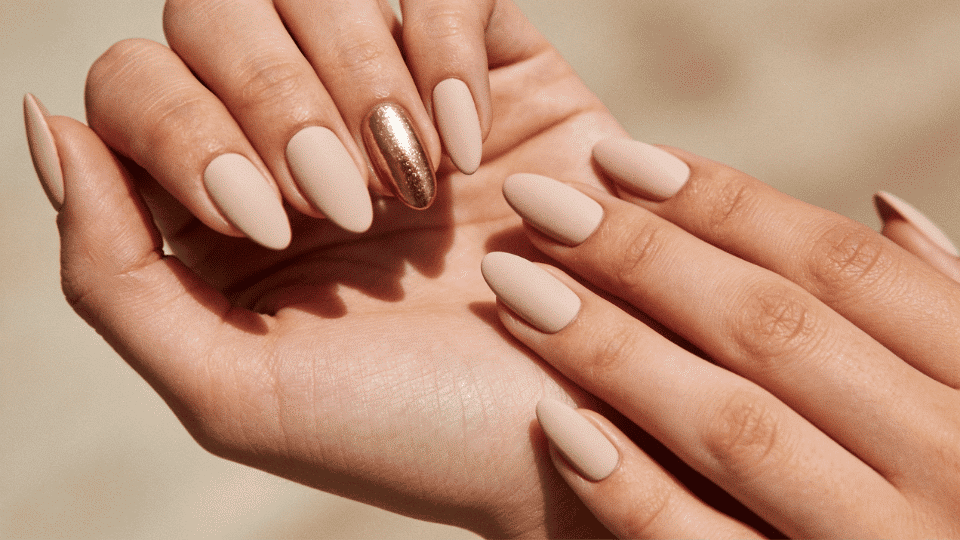 Hands with almond nails in matte nude with a glossy accent nail, stylish and balanced look.