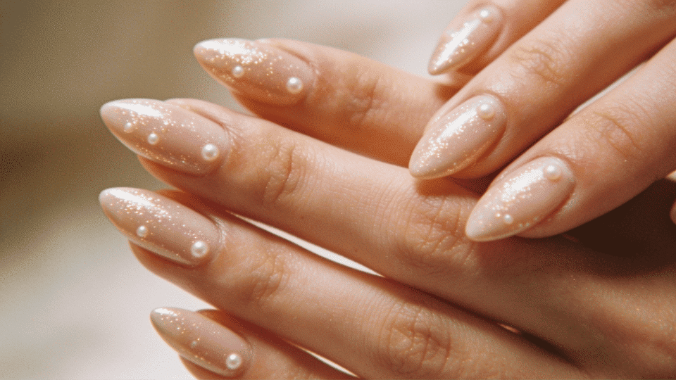 Hands showing almond nails with nude base and subtle shimmer, glossy pearl finish for understated summer look.