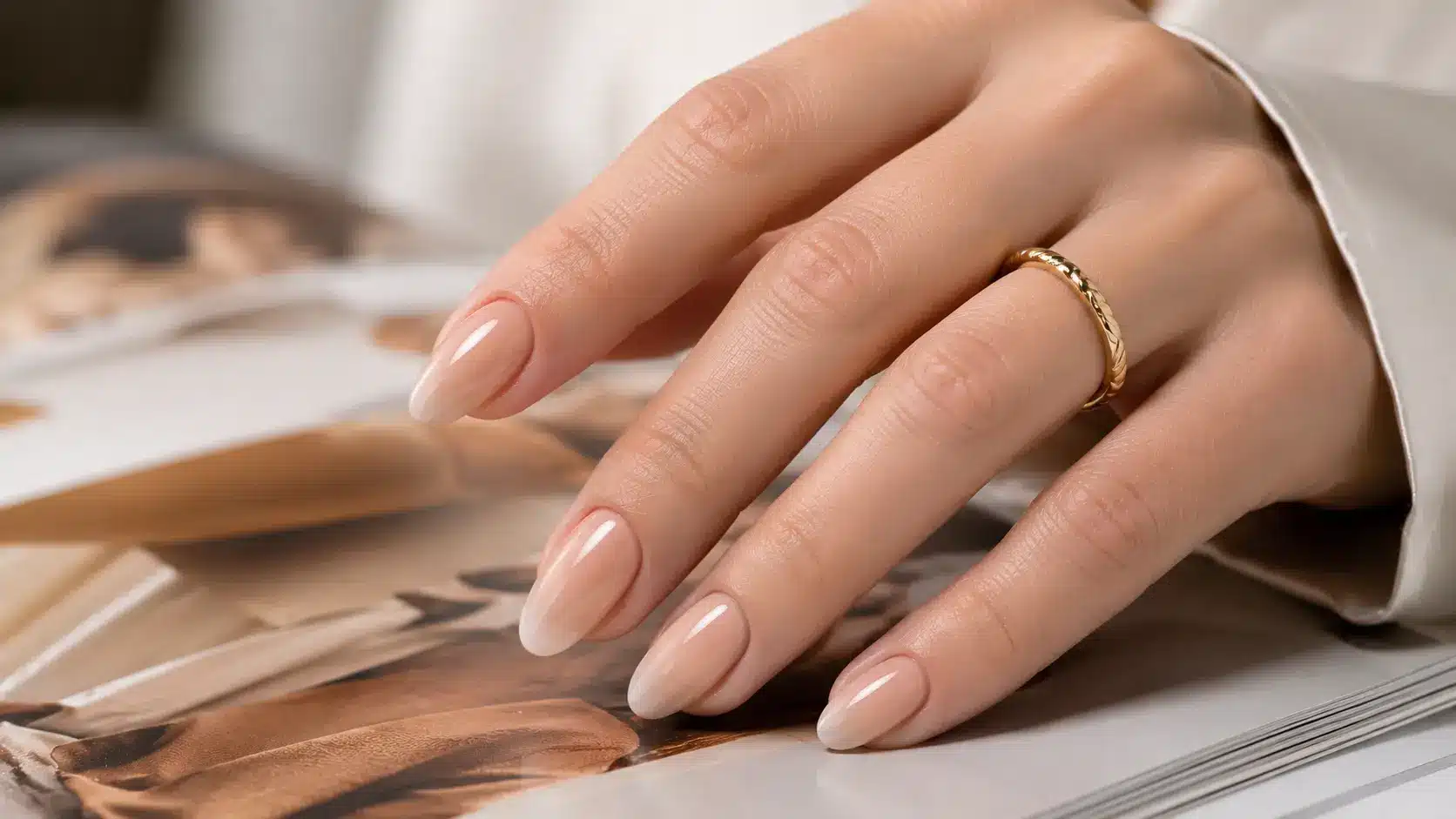 Nude beige ombre nails resting on an open magazine