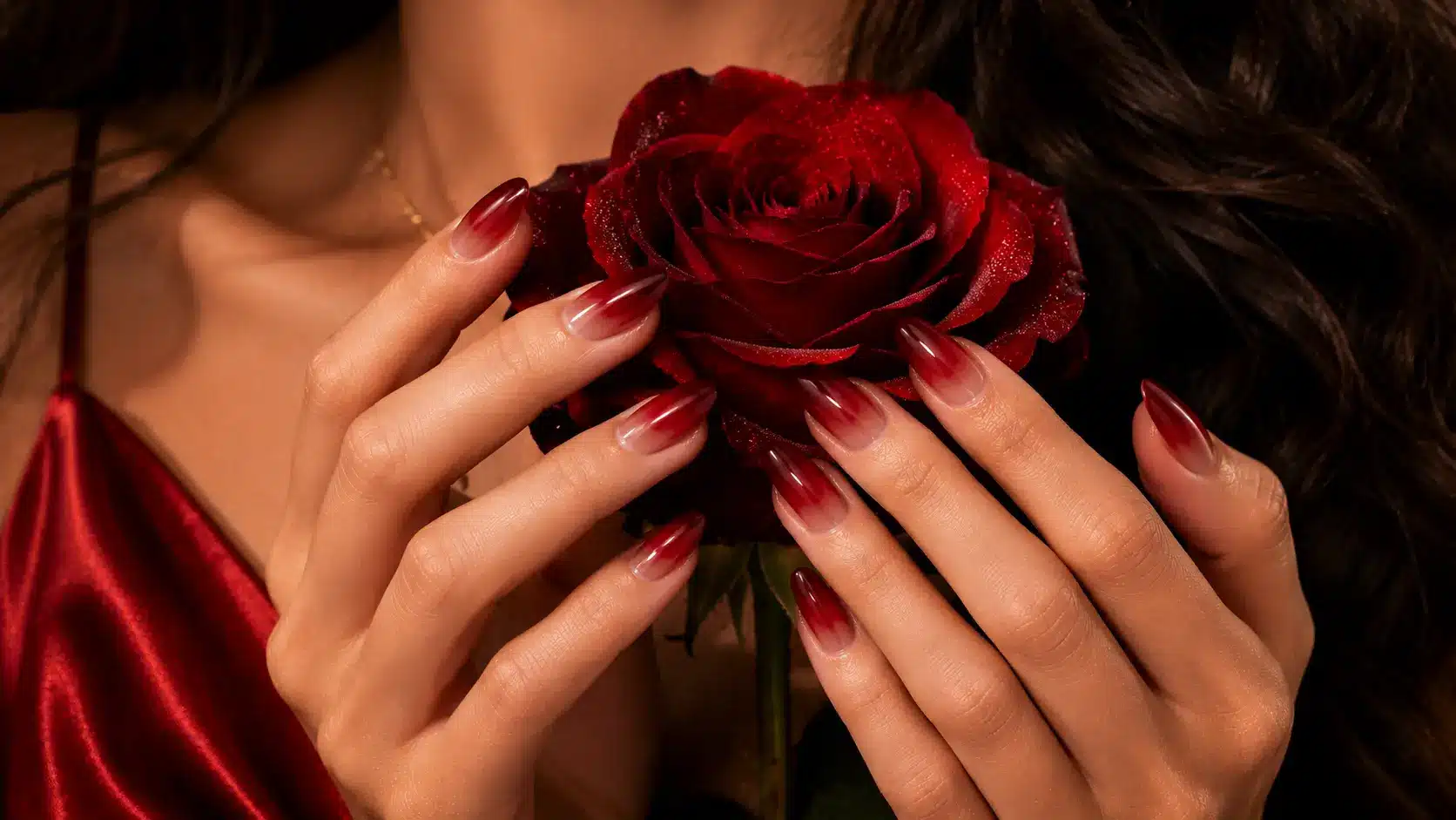 Red ombre nails holding a red rose
