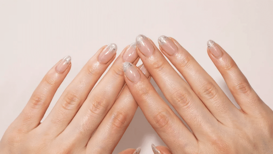 Almond-shaped nails with delicate glitter tips on glossy base, festive elegant manicure.