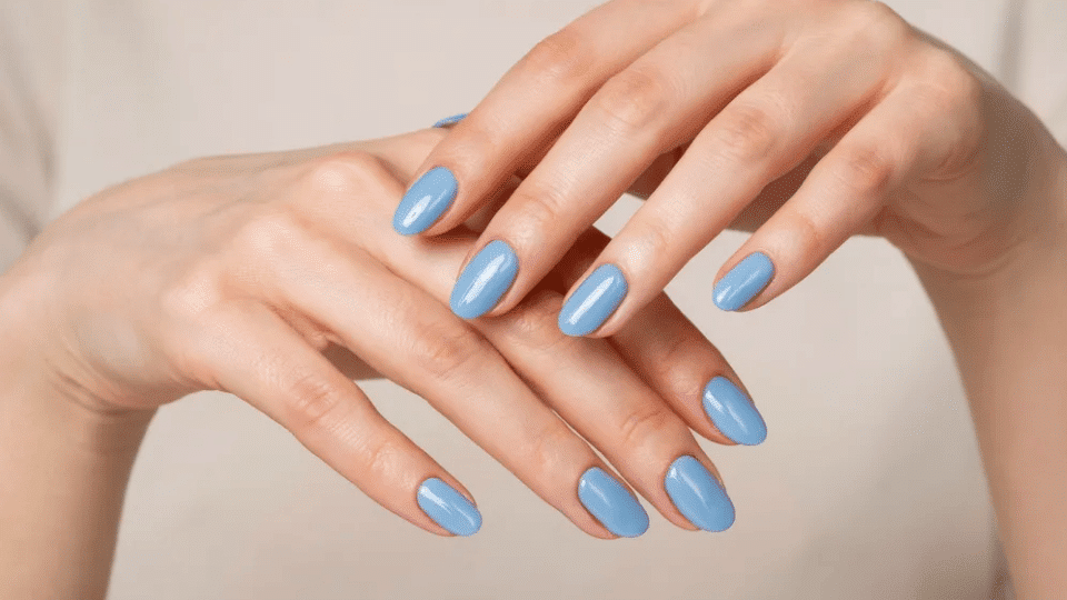 Hands showing almond nails in sky blue with glossy finish, light and airy summer-inspired manicure.