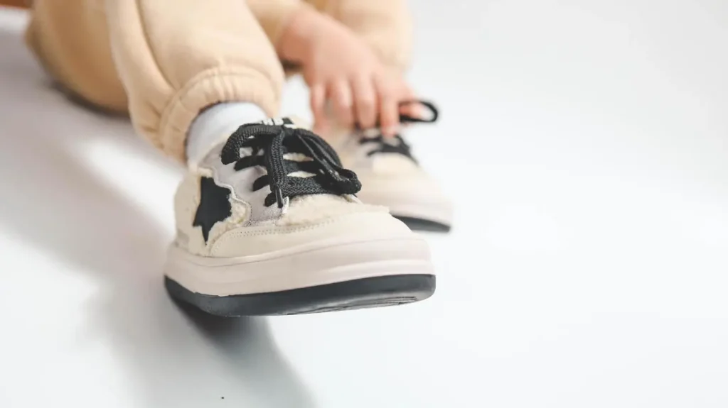 Close-up of child's beige sneakers with black laces on white background
