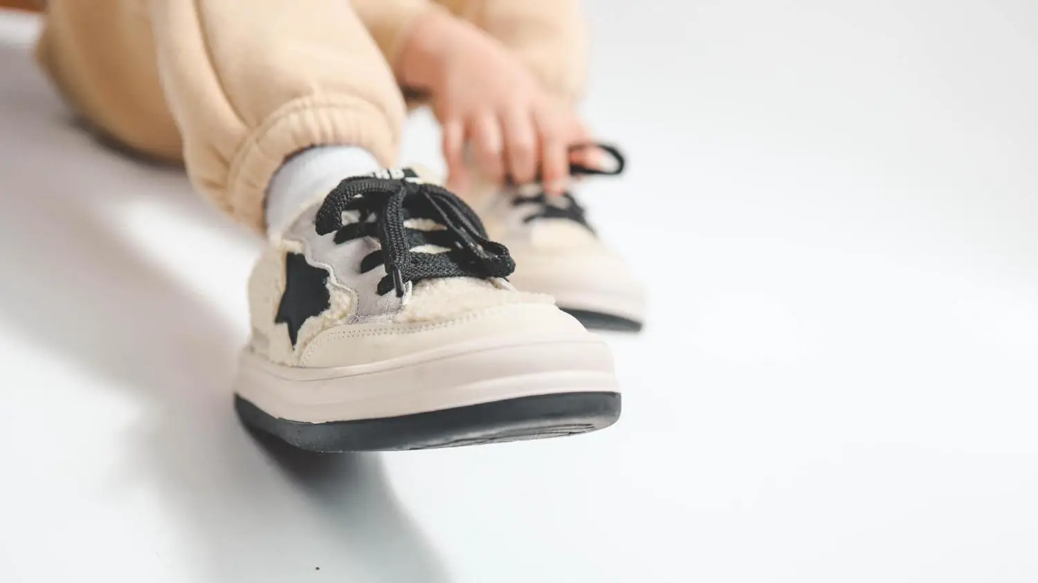 Close-up of child's beige sneakers with black laces on white background