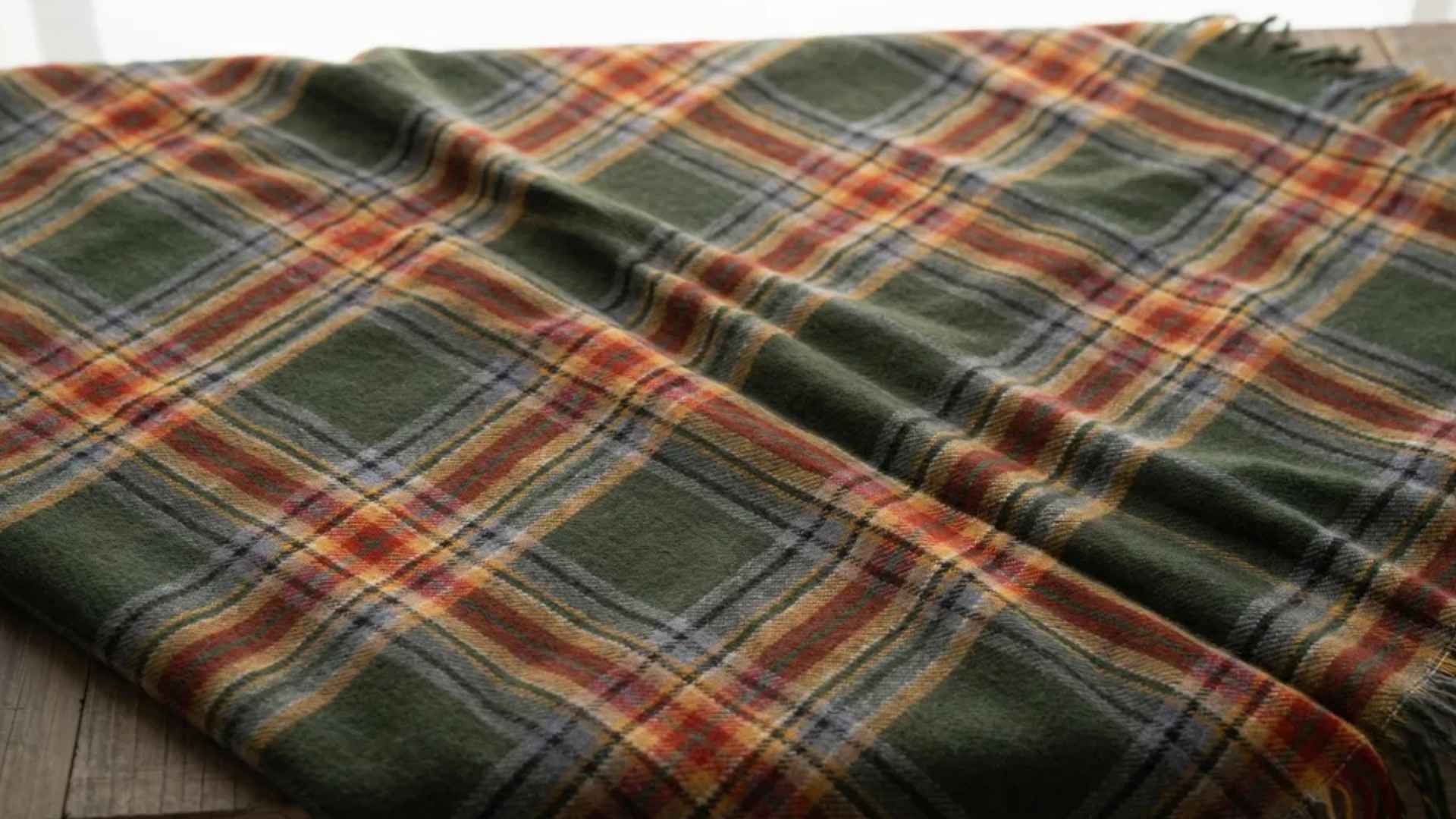 Close-up of a multi-colored plaid fabric with intersecting horizontal and vertical lines, layered texture.