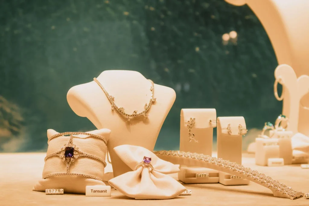 Jewelry display featuring necklaces, bracelets, and rings under soft lighting in a showroom setting